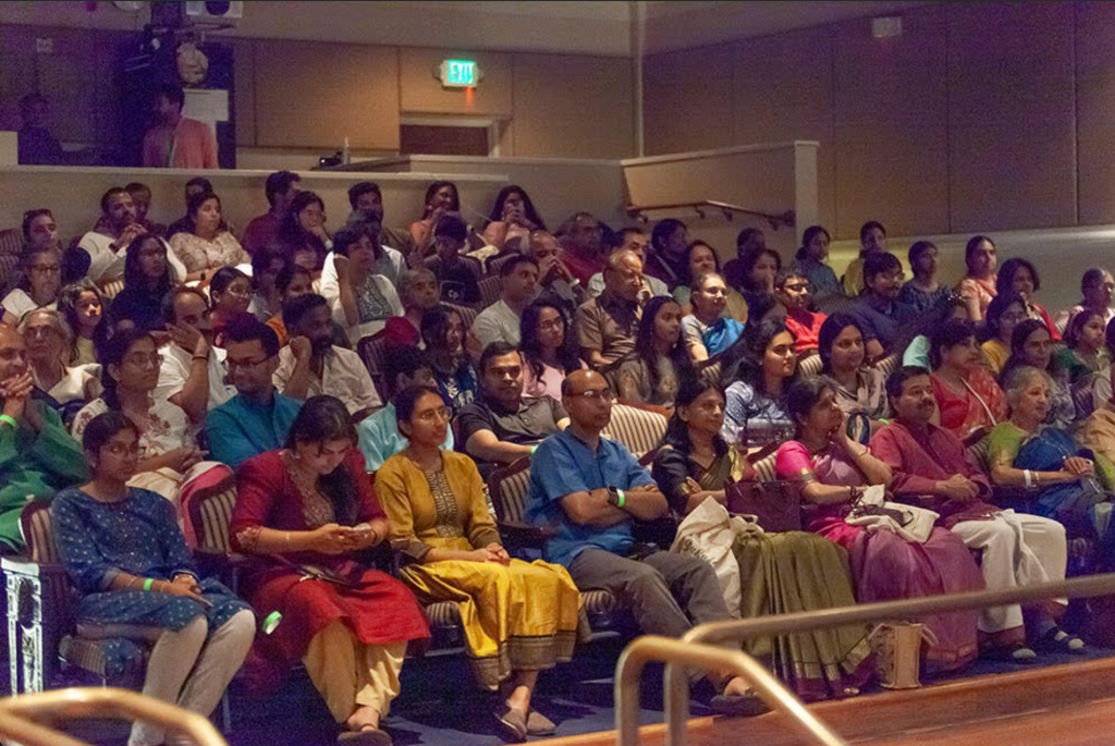 A large seated audience watching a performance