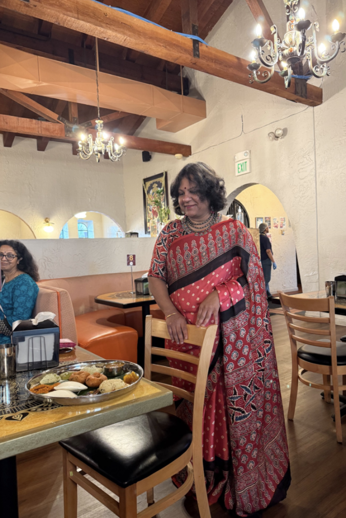 A steel plate of idli, vadai, pongal and chutneys on a restaurant table